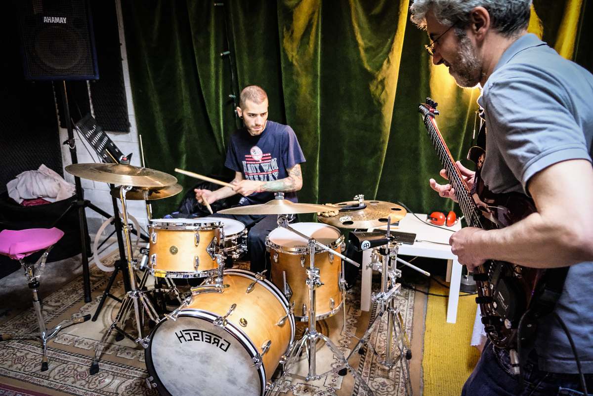 person man in blue t-shirt playing drum set musician